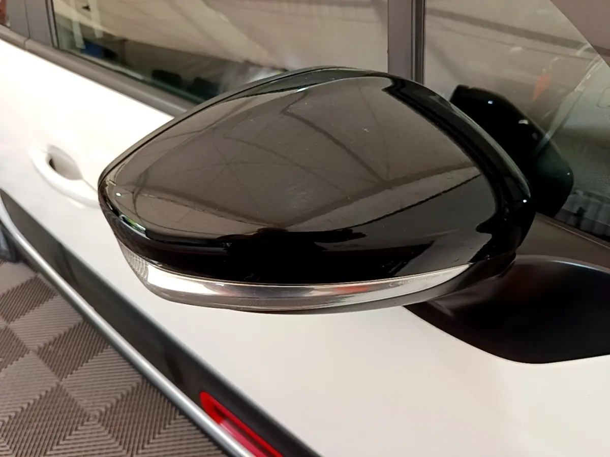 Rétroviseur noir avec clignotant intégré sur la porte blanche côté gauche d'une Citroën C3 2021.