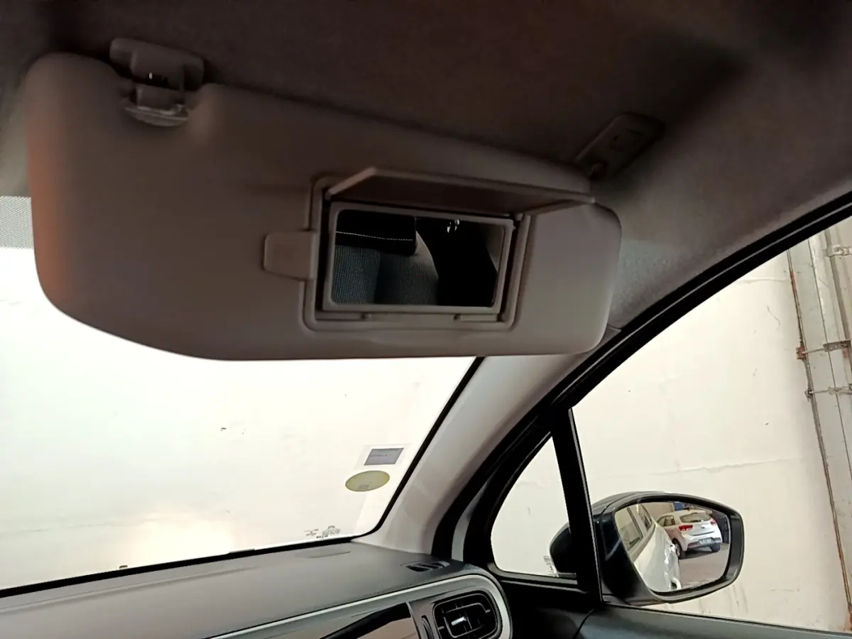 Intérieur côté conducteur de la Citroën C3 blanche 2021, avec pare-soleil rabattable et miroir de courtoisie ouvert.