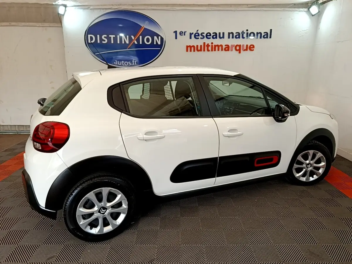 Vue latérale droite d'une Citroën C3 blanche 2021 avec protections noires et insert rouge sur la porte arrière.