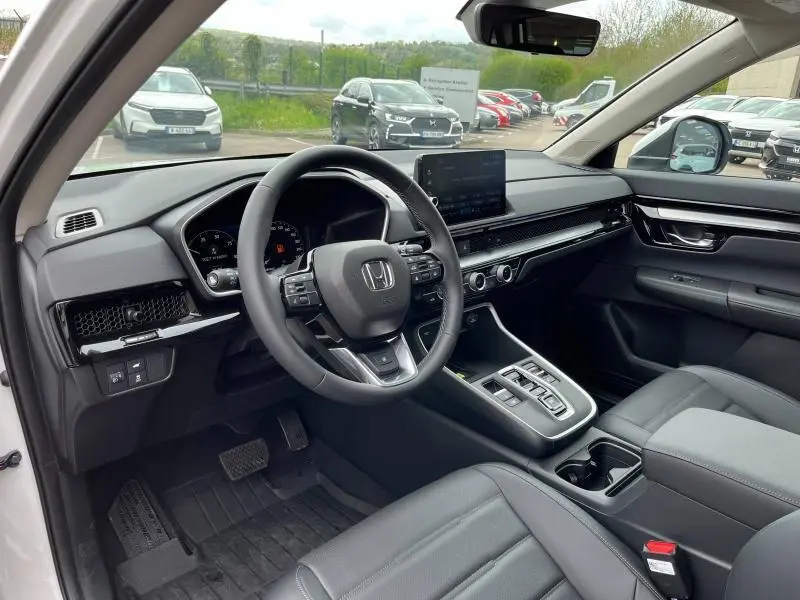 Intérieur du Honda CR-V blanc platine nacré 2024, vue côté conducteur avec tableau de bord moderne et volant cuir multifonction.