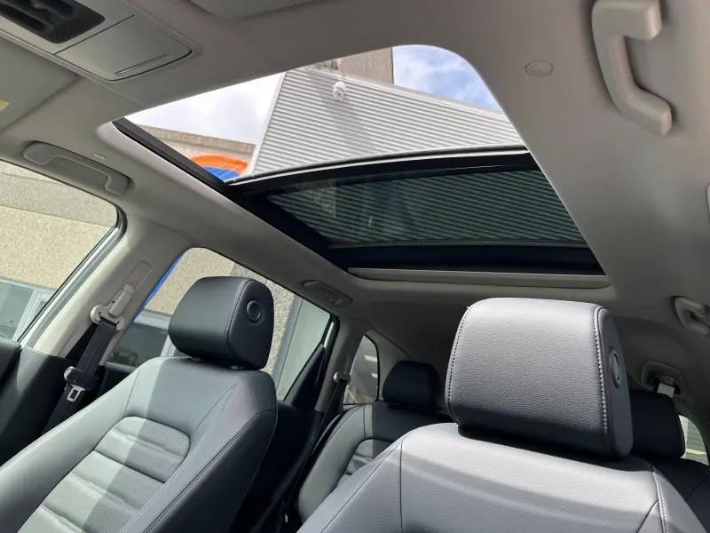 Intérieur du Honda CR-V 2024 blanc nacré, vue sur sièges cuir noirs et toit panoramique vitré ouvert.