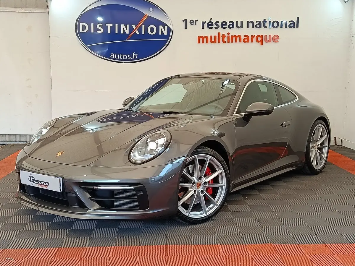 Porsche 911 Carrera 4S Coupé gris foncé vue 3/4 avant droit, jantes argent et étriers rouges visibles