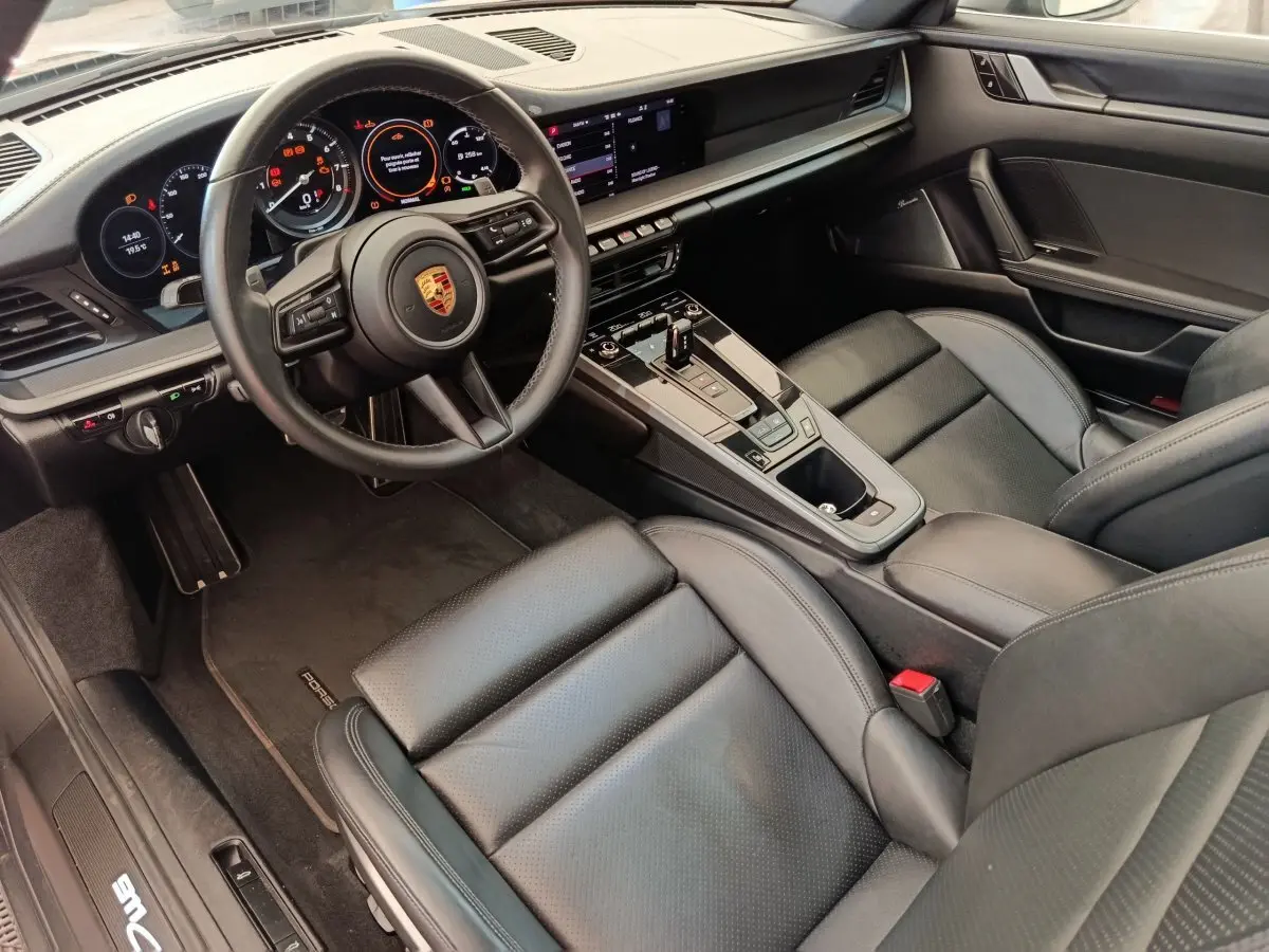 Intérieur noir du Porsche 911 Carrera 4S 2019 vu côté conducteur, avec tableau de bord numérique et volant cuir.