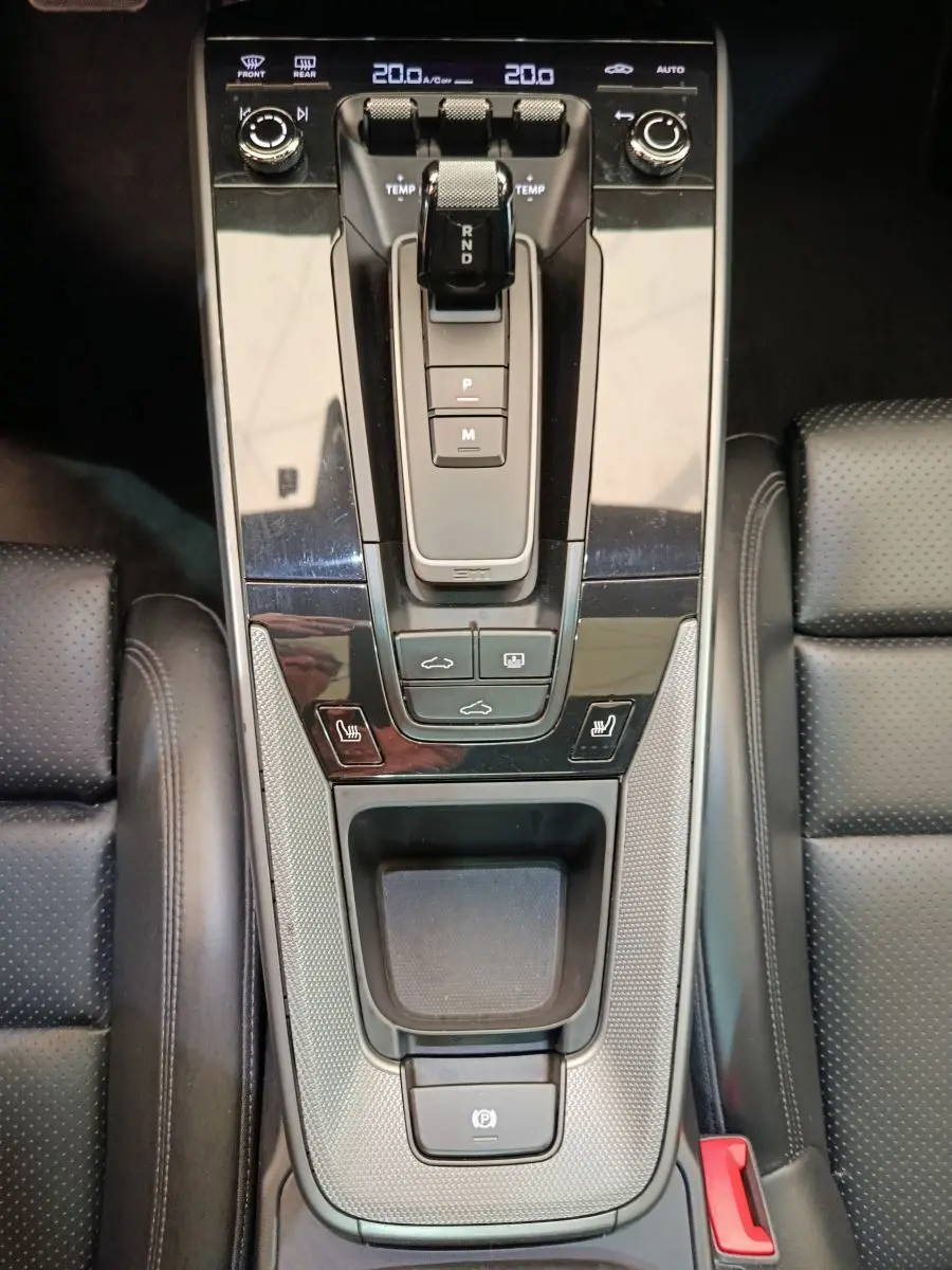 Vue plongeante sur la console centrale noire du Porsche 911 Carrera 4S 2019 avec levier de vitesse automatique et sièges cuir perforé.