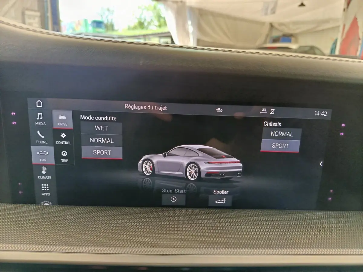 Écran tactile intérieur affichant une Porsche 911 Carrera 4S Coupé gris foncé vue de 3/4 arrière en mode sport.