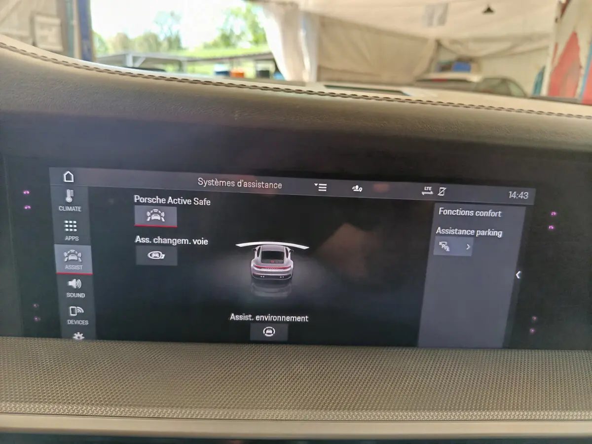 Écran tactile central affichant les aides à la conduite dans l'habitacle d'une Porsche 911 Carrera 4S Coupé gris foncé.