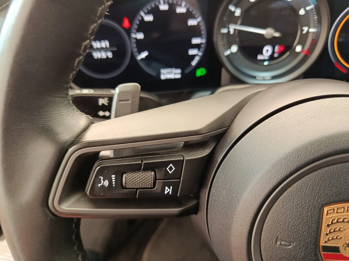 Gros plan sur le volant cuir noir de la Porsche 911 Carrera 4S 2019 avec commandes multifonctions et tableau de bord numérique.