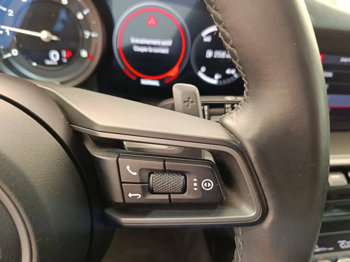 Gros plan sur les commandes au volant cuir noir de la Porsche 911 Carrera 4S Coupé 2019 avec tableau de bord numérique.