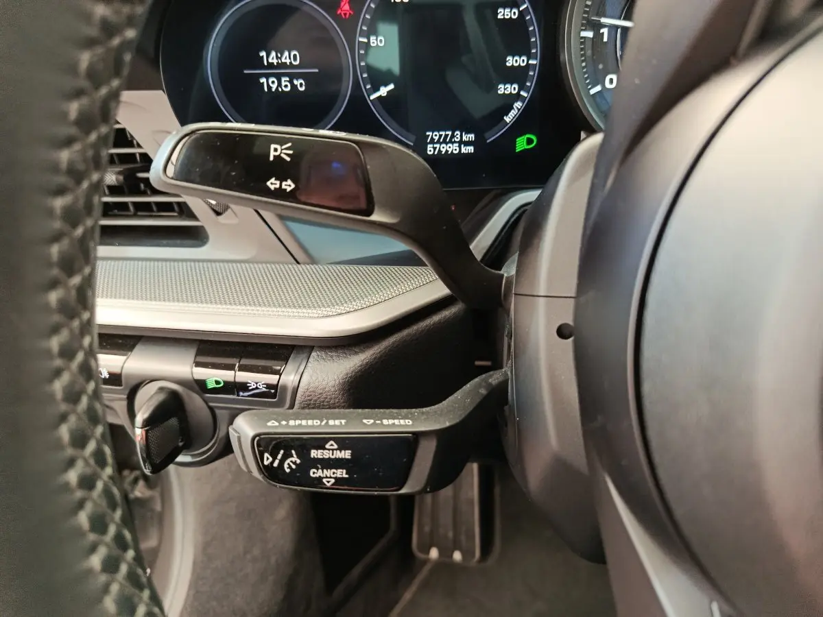 Gros plan sur le volant et les commandes au volant d'une Porsche 911 Carrera 4S Coupé gris foncé, tableau de bord numérique visible.