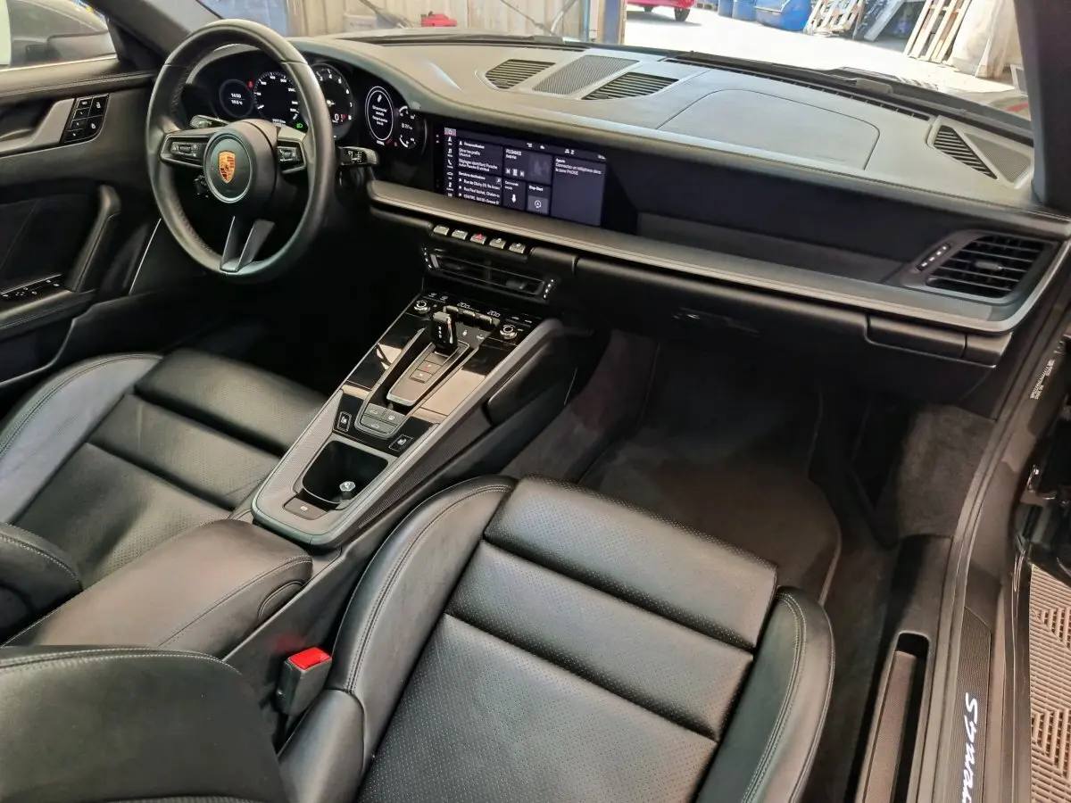 Intérieur noir de la Porsche 911 Carrera 4S 2019 vu côté passager, avec tableau de bord digital et console centrale moderne.