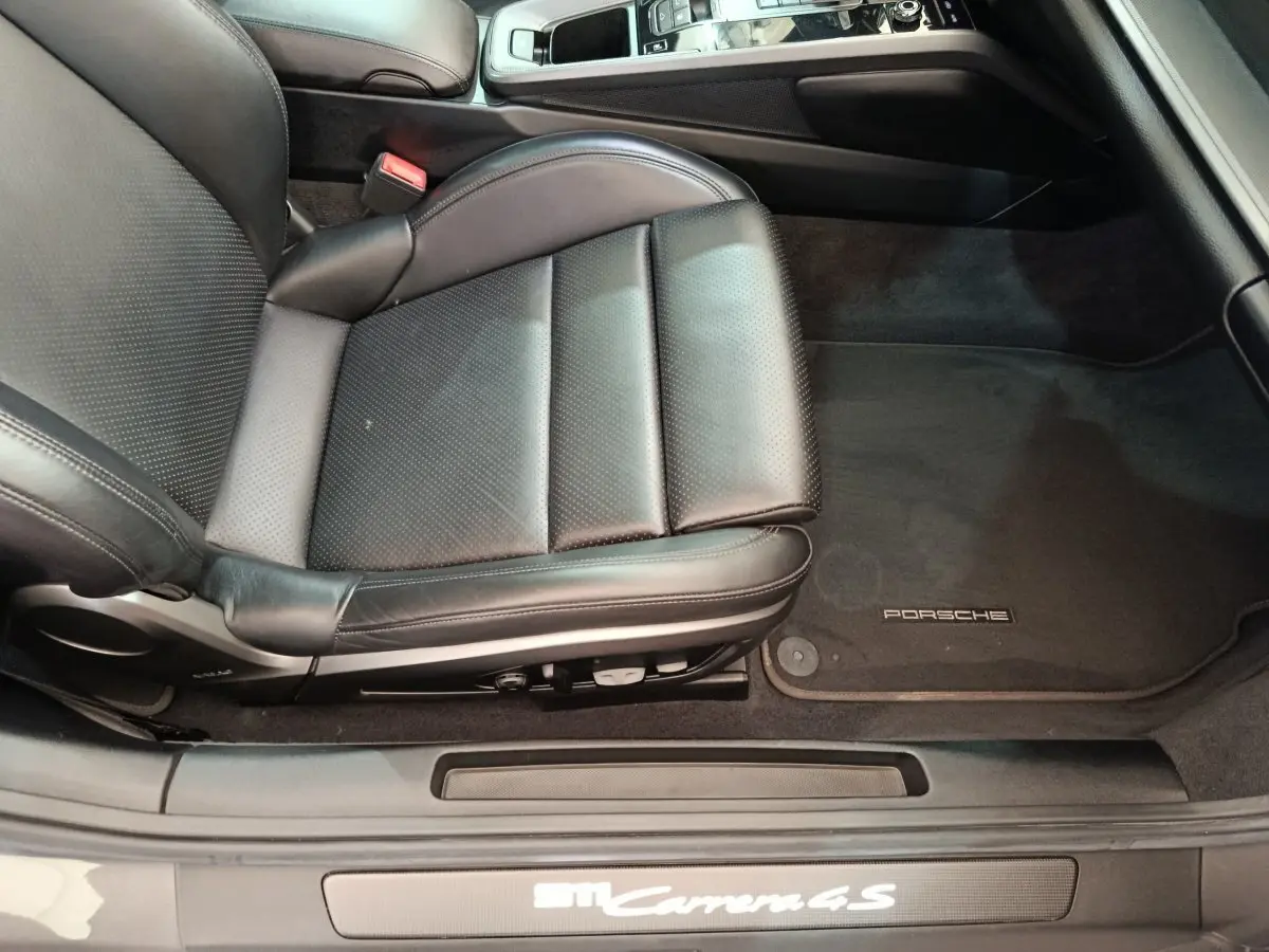 Vue rapprochée du siège conducteur en cuir noir et tapis de sol Porsche d'une Porsche 911 Carrera 4S Coupé 2019.