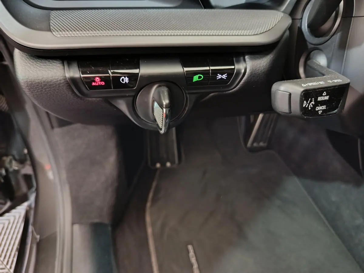 Gros plan sur les commandes d'éclairage et régulateur de vitesse du tableau de bord noir d'une Porsche 911 Carrera 4S 2019.