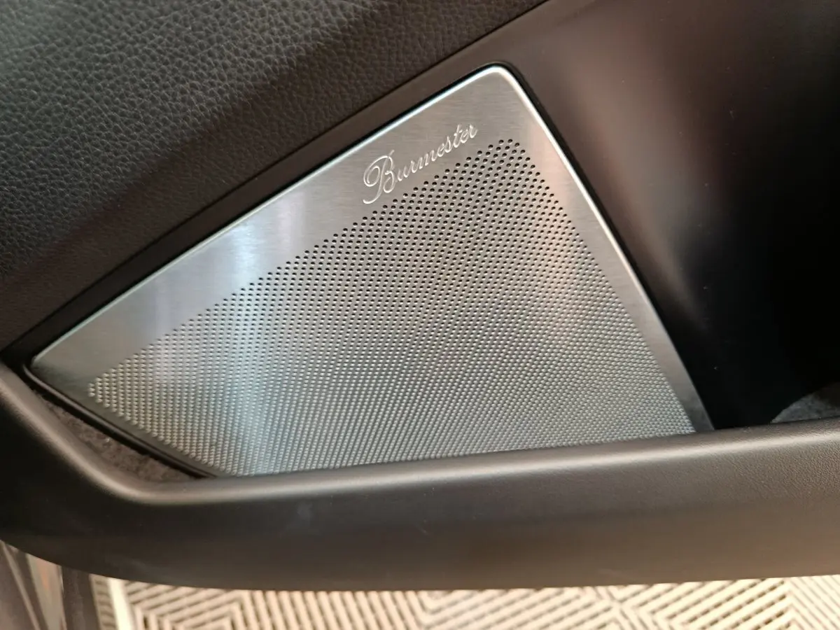 Gros plan sur le haut-parleur Burmester intégré à la porte intérieure noire de la Porsche 911 Carrera 4S Coupé gris foncé.