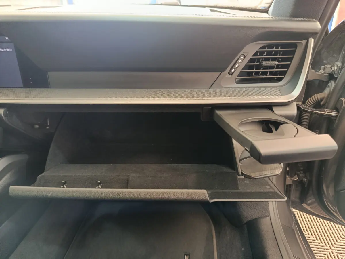 Intérieur côté passager d'une Porsche 911 Carrera 4S 2019, boîte à gants ouverte avec porte-gobelet déployé, finition gris foncé.