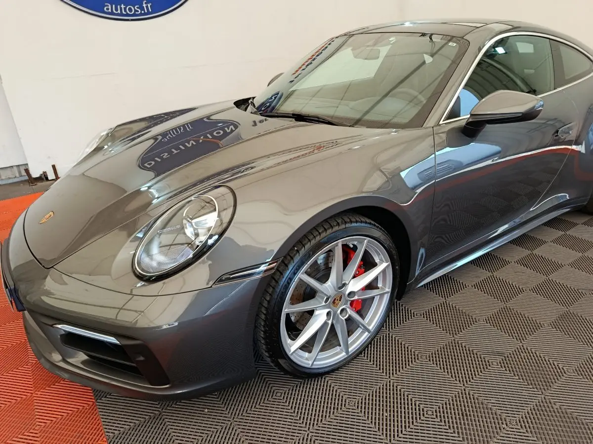 Porsche 911 Carrera 4S Coupé gris foncé vue 3/4 avant droit avec jantes alliage et étriers rouges visibles