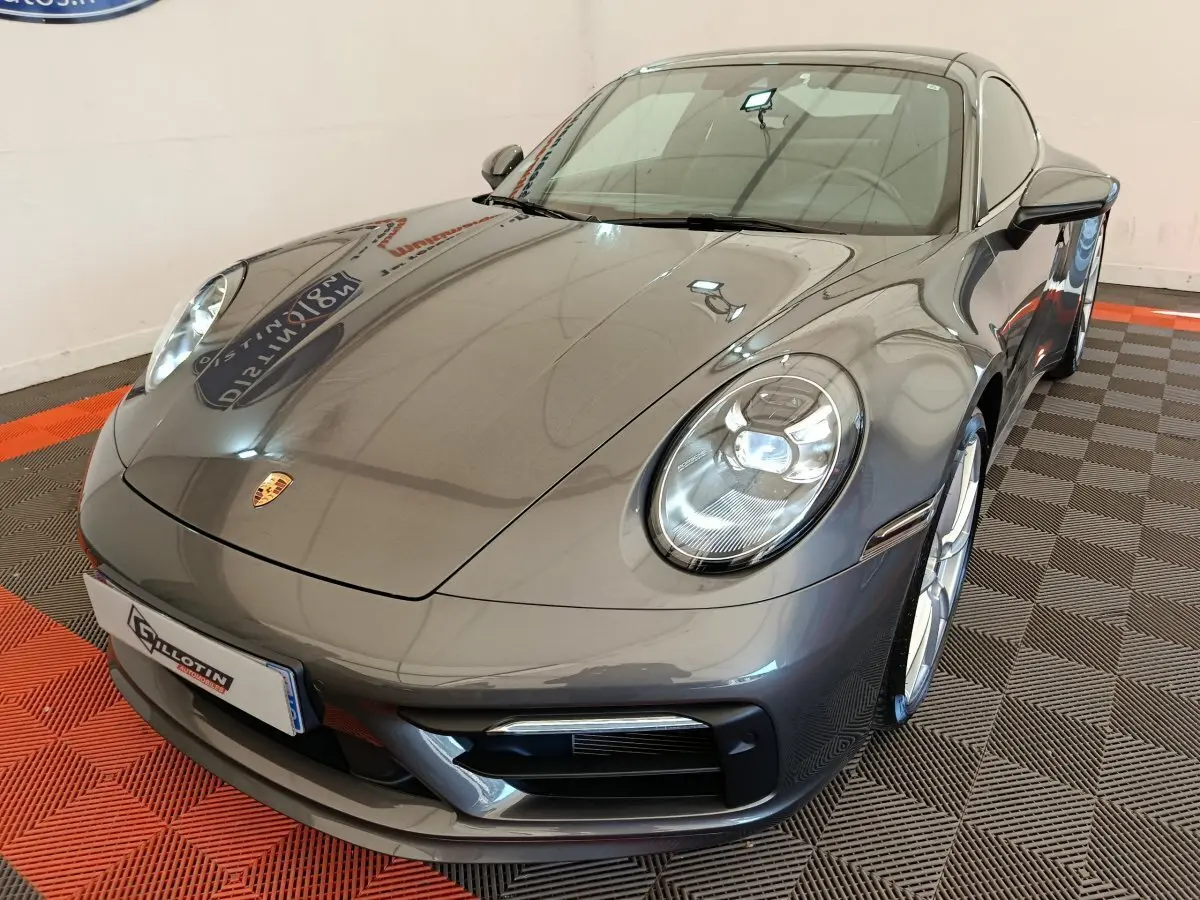 Vue 3/4 avant droite d'une Porsche 911 Carrera 4S Coupé gris foncé brillant avec phares LED et jantes argentées.