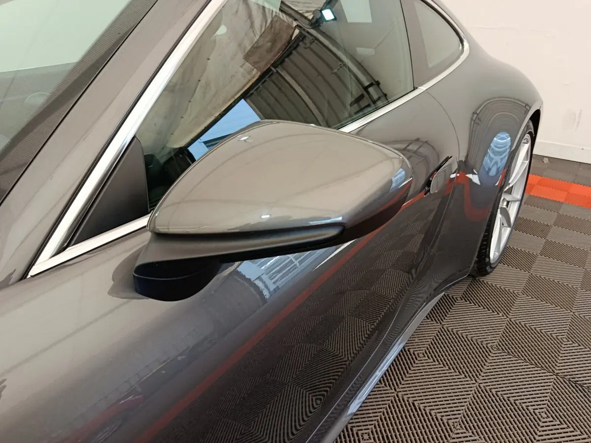 Gros plan sur le rétroviseur côté gauche d'une Porsche 911 Carrera 4S Coupé gris foncé, avec la porte et la roue arrière visibles.