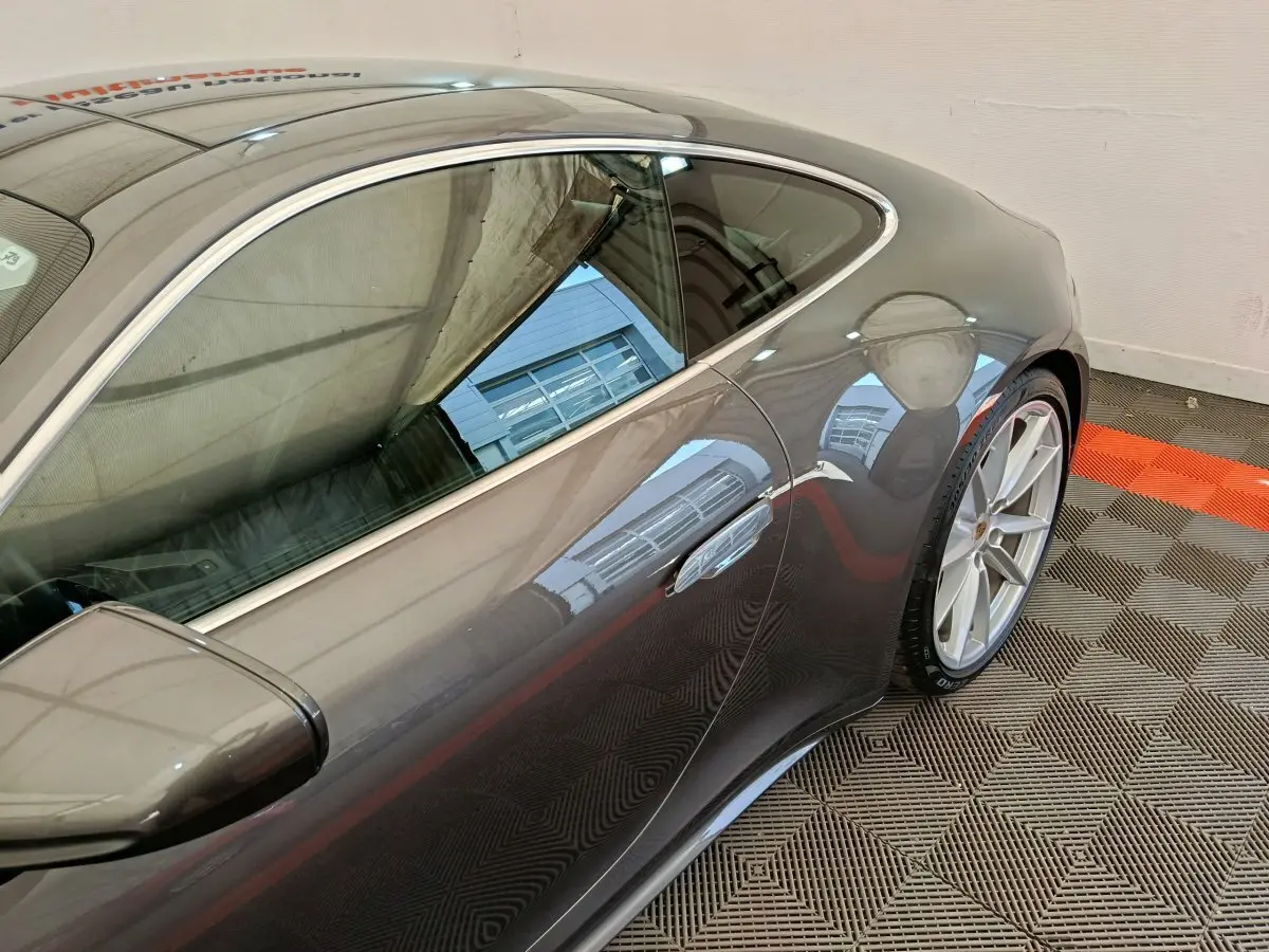 Vue latérale côté droit d'une Porsche 911 Carrera 4S Coupé gris foncé, soulignant la ligne fluide et les jantes sport.