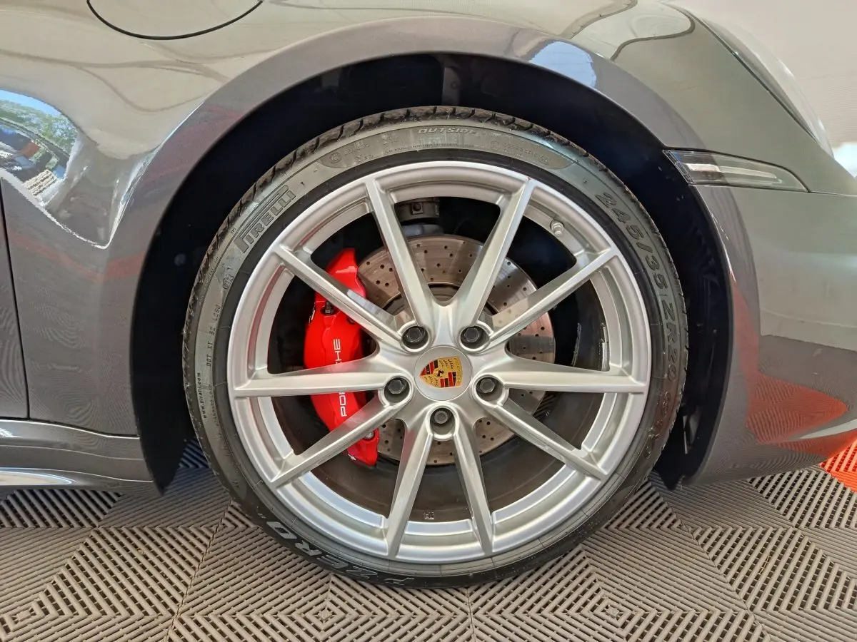 Gros plan sur la roue avant droite grise d'une Porsche 911 Carrera 4S avec étrier de frein rouge et jante argentée.