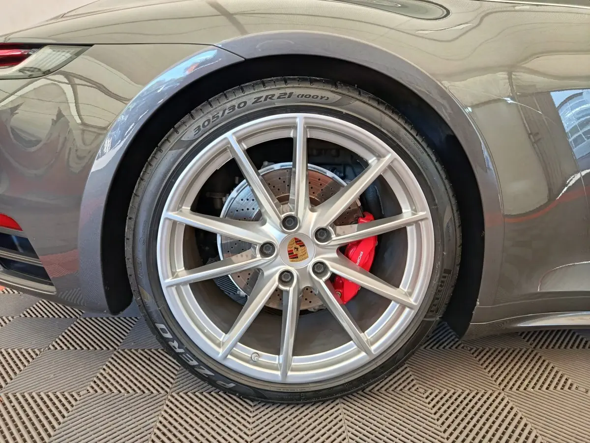 Gros plan sur la roue arrière droite grise d'une Porsche 911 Carrera 4S avec étrier de frein rouge visible.