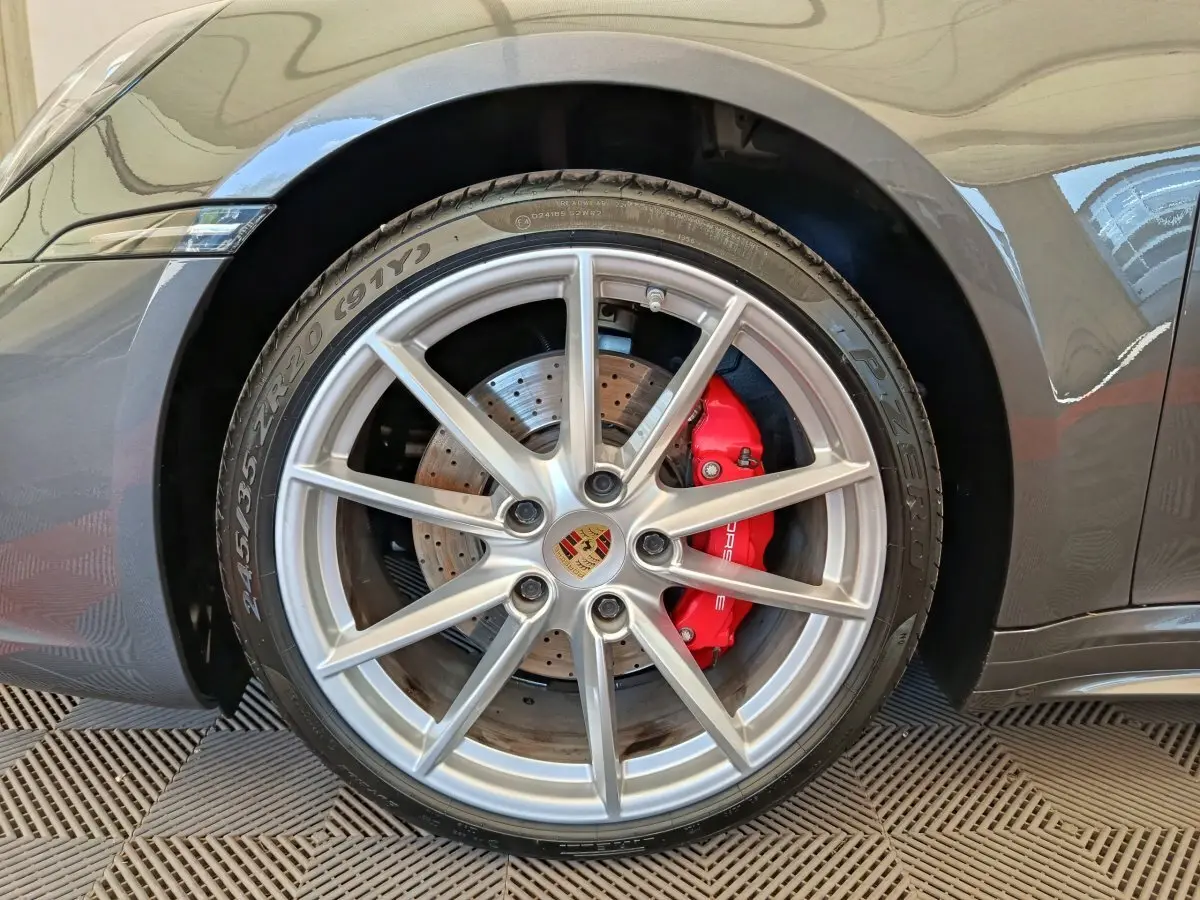 Gros plan sur la roue avant droite grise d'une Porsche 911 Carrera 4S avec étrier de frein rouge et jante argentée.
