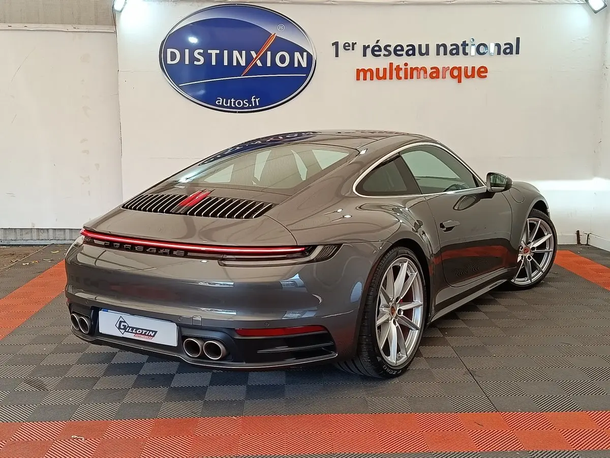 Vue 3/4 arrière droite d'une Porsche 911 Carrera 4S Coupé gris foncé avec feux LED et quadruple sortie d'échappement.