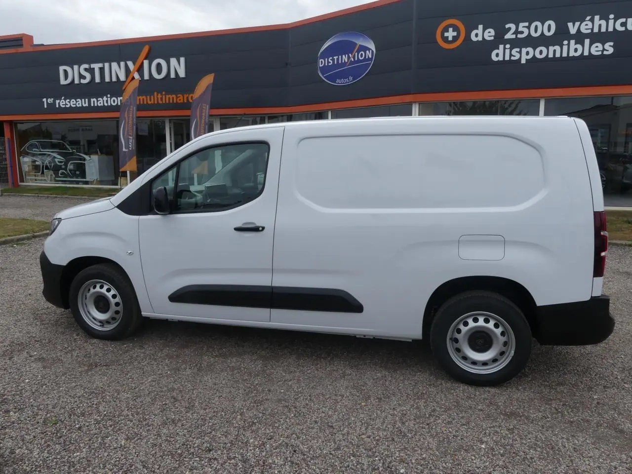 Vue de profil côté gauche d'un utilitaire Peugeot Partner blanc avec porte latérale coulissante et jantes tôles grises.