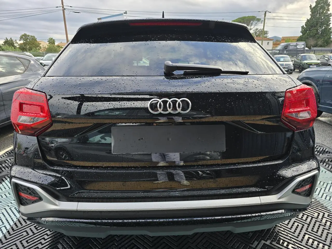 Vue arrière d'un Audi Q2 noir mythic 2023 avec feux rouges et lunette arrière surteintée.