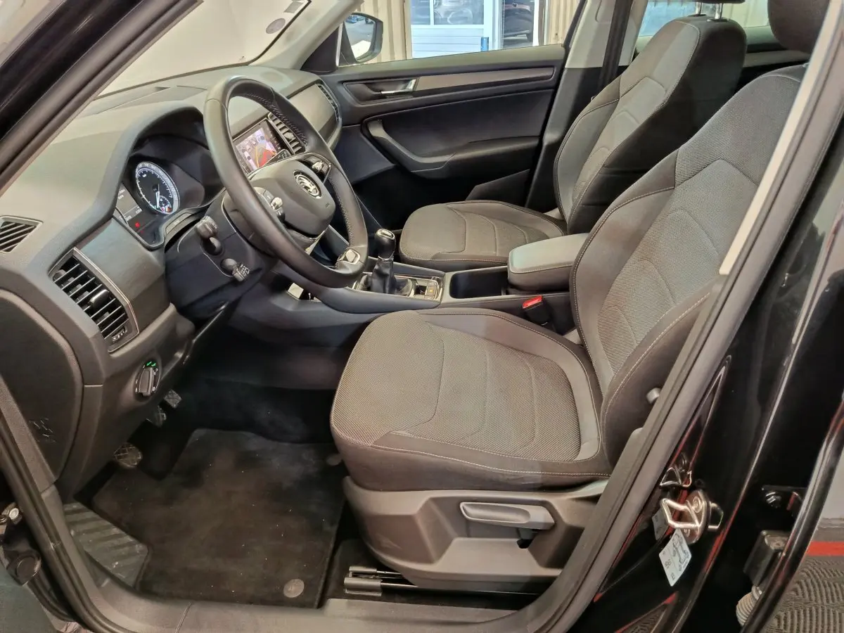 Intérieur avant du Skoda Kodiaq noir 2021, vue côté conducteur montrant sièges tissu gris et tableau de bord moderne.
