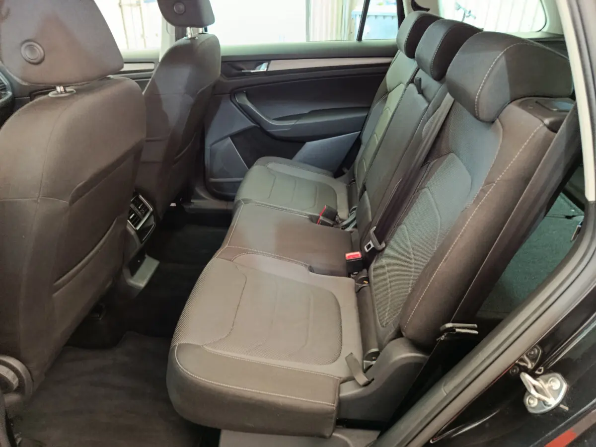Vue latérale intérieure côté droit du Skoda Kodiaq noir 2021, montrant la banquette arrière en tissu gris avec appuie-têtes.