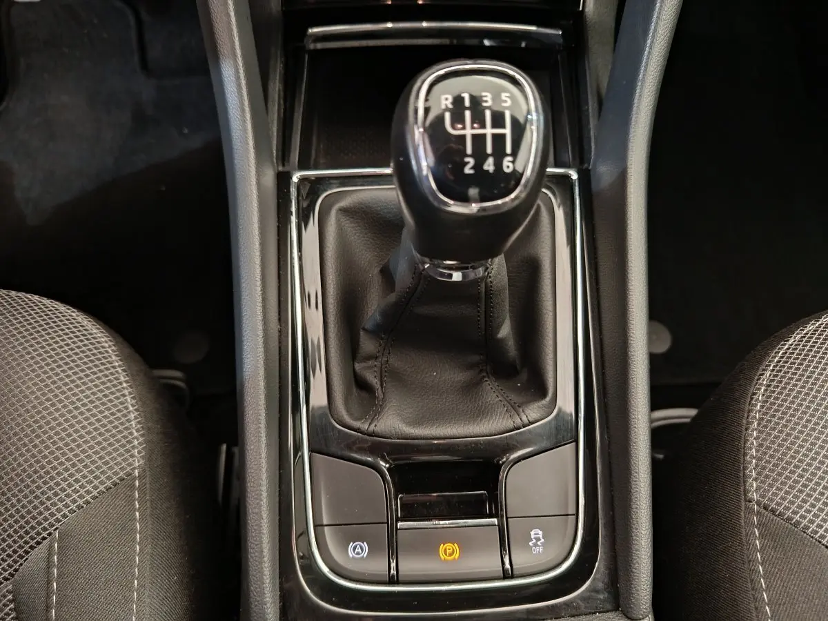 Gros plan sur le levier de vitesses manuel noir du Skoda Kodiaq 2021, entouré des sièges avant en tissu gris.