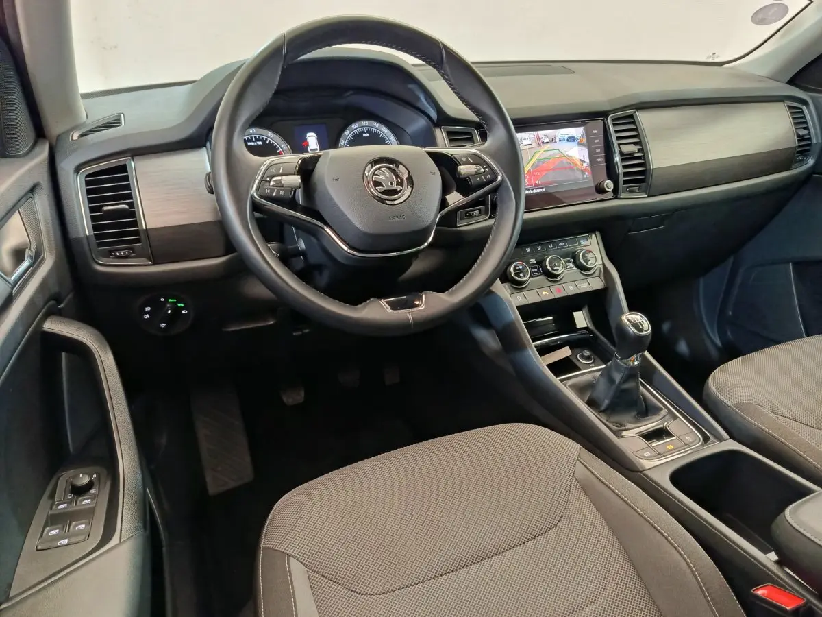 Vue intérieure avant centrée sur le volant cuir Skoda Kodiaq noir, tableau de bord avec écran tactile et levier de vitesse manuel.