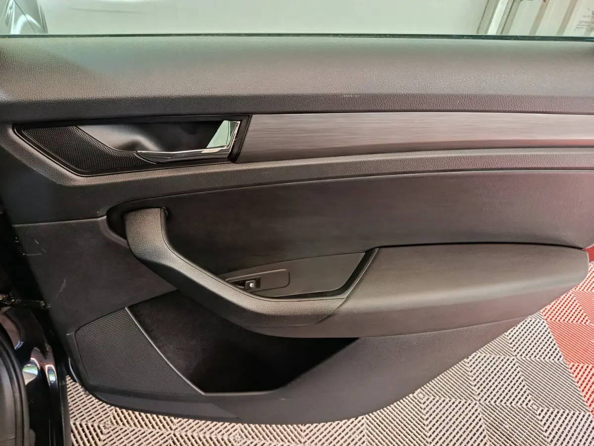 Gros plan sur la porte intérieure côté conducteur du Skoda Kodiaq noir, avec poignée chromée et garniture noire.