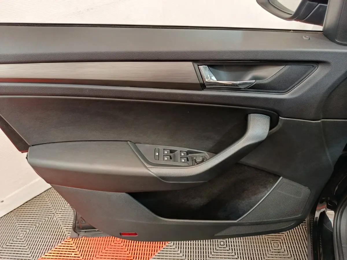 Intérieur côté gauche de la porte avant d'un Skoda Kodiaq noir, avec commandes de vitres et poignée intégrée.
