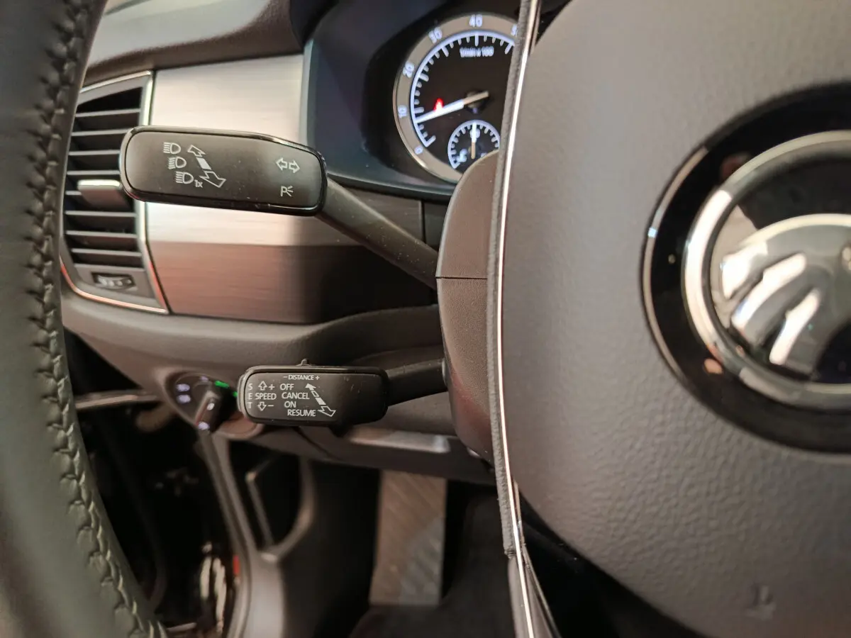 Gros plan sur le volant cuir noir et les commandes de clignotants et régulateur de vitesse du Skoda Kodiaq Ambition 2021.