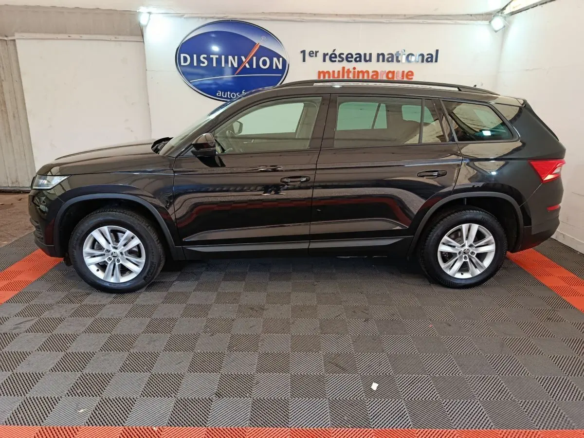 Profil droit d'un SUV SKODA KODIAQ noir 2021 avec toit noir mat et jantes argentées en intérieur showroom