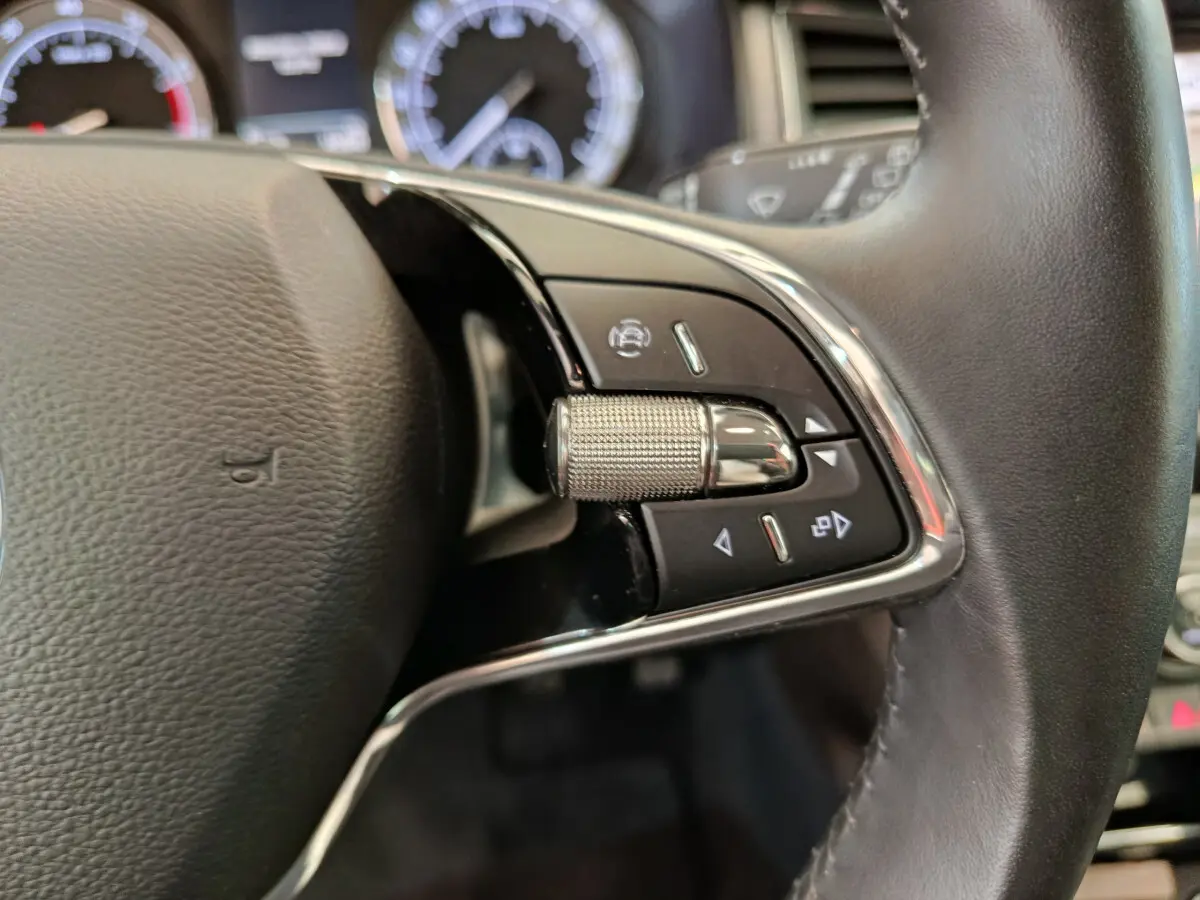 Gros plan sur la partie droite du volant cuir du Skoda Kodiaq noir, avec commandes multifonctions et molette métallique.