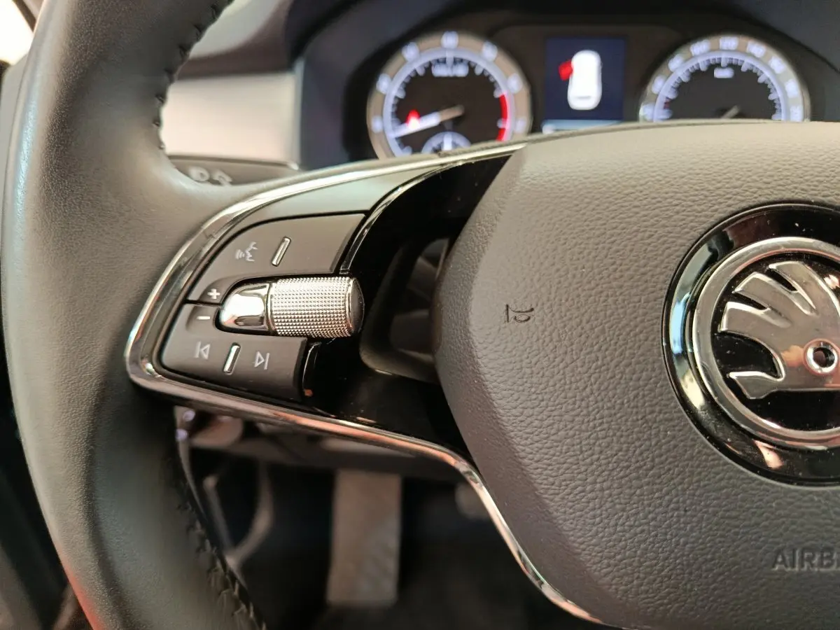 Gros plan sur le volant cuir noir du Skoda Kodiaq 2021, avec commandes multifonctions et logo central chrome.