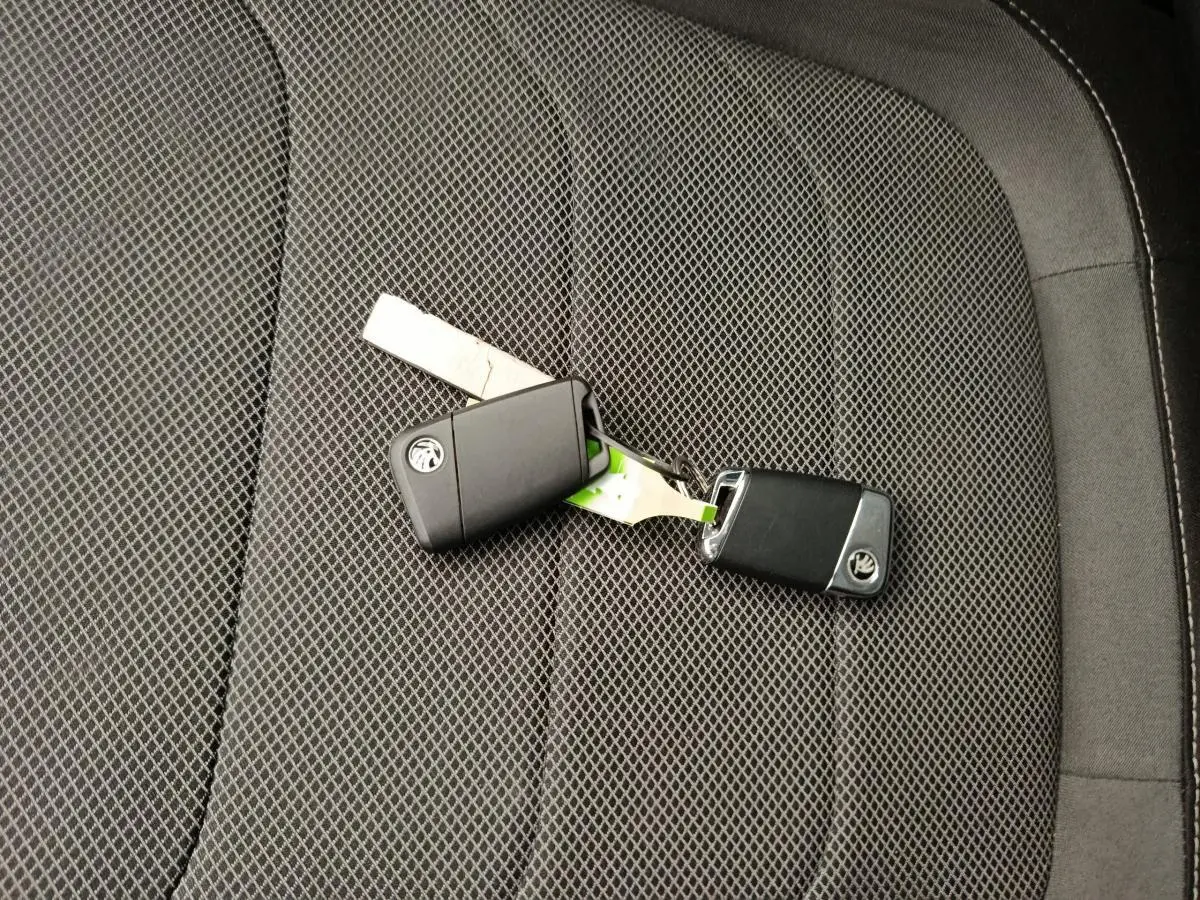 Clé de voiture SKODA posée sur un siège tissu noir à motifs géométriques à l'intérieur du KODIAQ 2021.