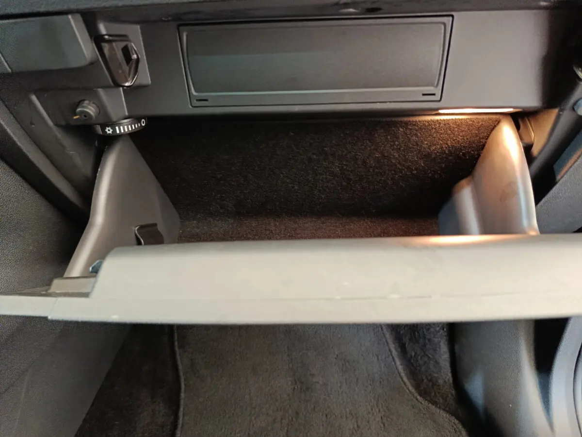 Vue rapprochée de la boîte à gants ouverte avec éclairage intérieur dans un Skoda Kodiaq noir 2021.