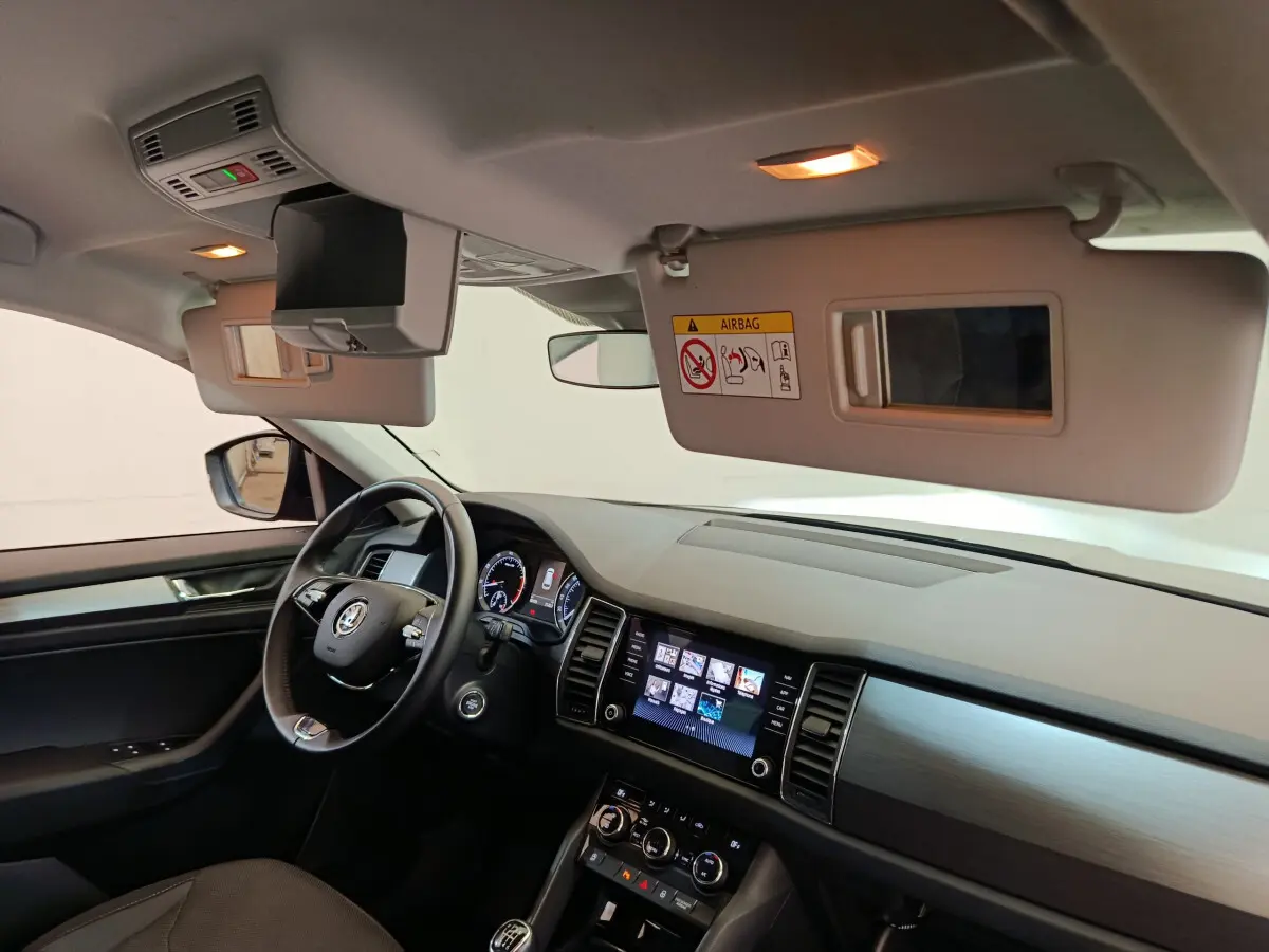 Intérieur avant du Skoda Kodiaq noir 2021, vue côté conducteur avec tableau de bord et écran tactile allumés.