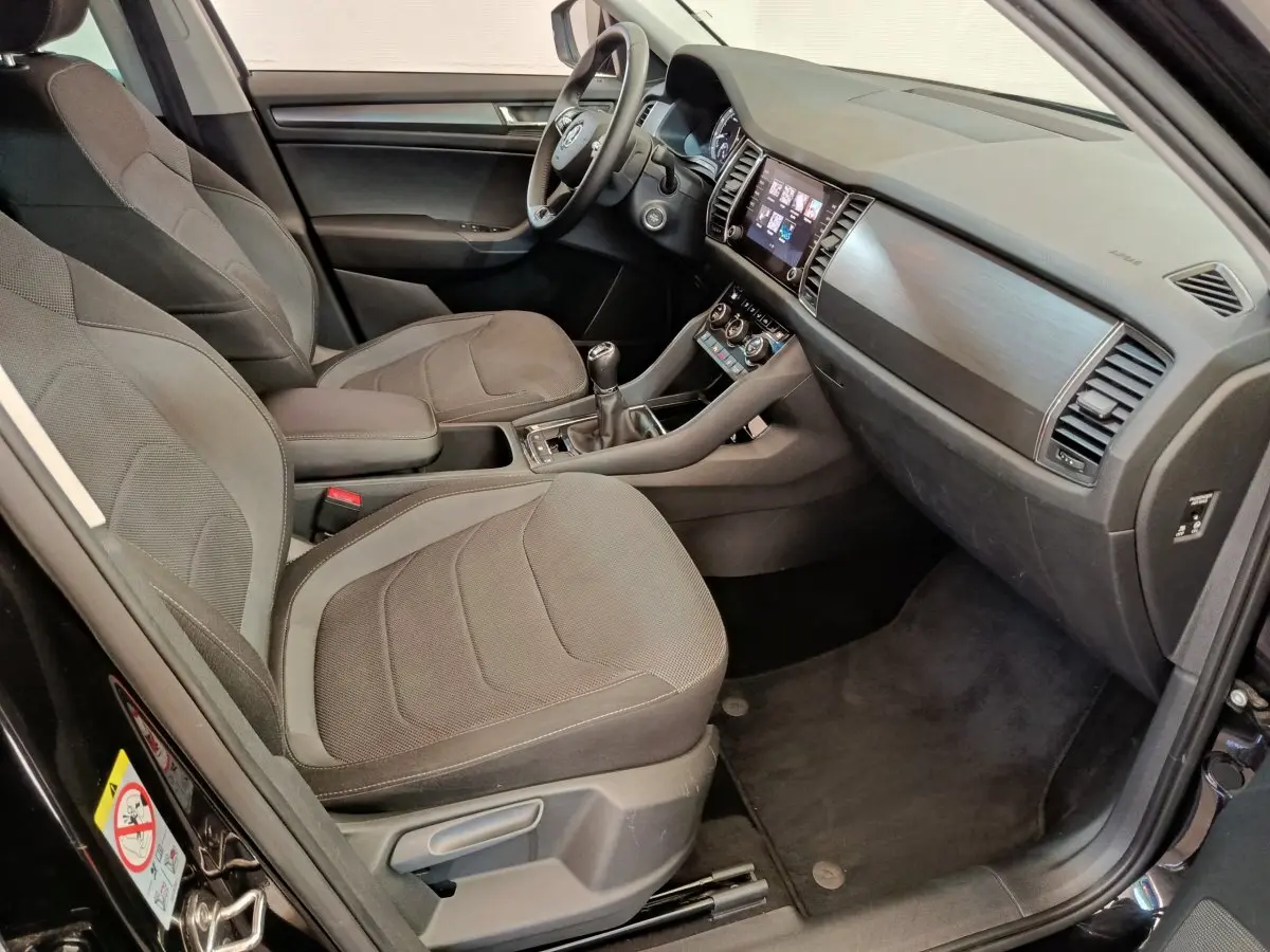 Intérieur avant du Skoda Kodiaq noir 2021, vue côté conducteur montrant sièges tissu et tableau de bord moderne.