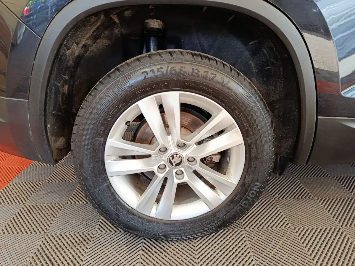 Gros plan sur la roue avant gauche noire d'un Skoda Kodiaq 2021 avec jante alliage argentée et logo central.