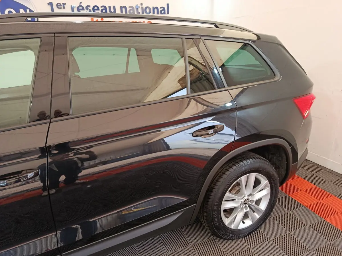 Vue latérale droite d'un SUV SKODA KODIAQ noir 2021 avec jantes alliage et barres de toit chromées.