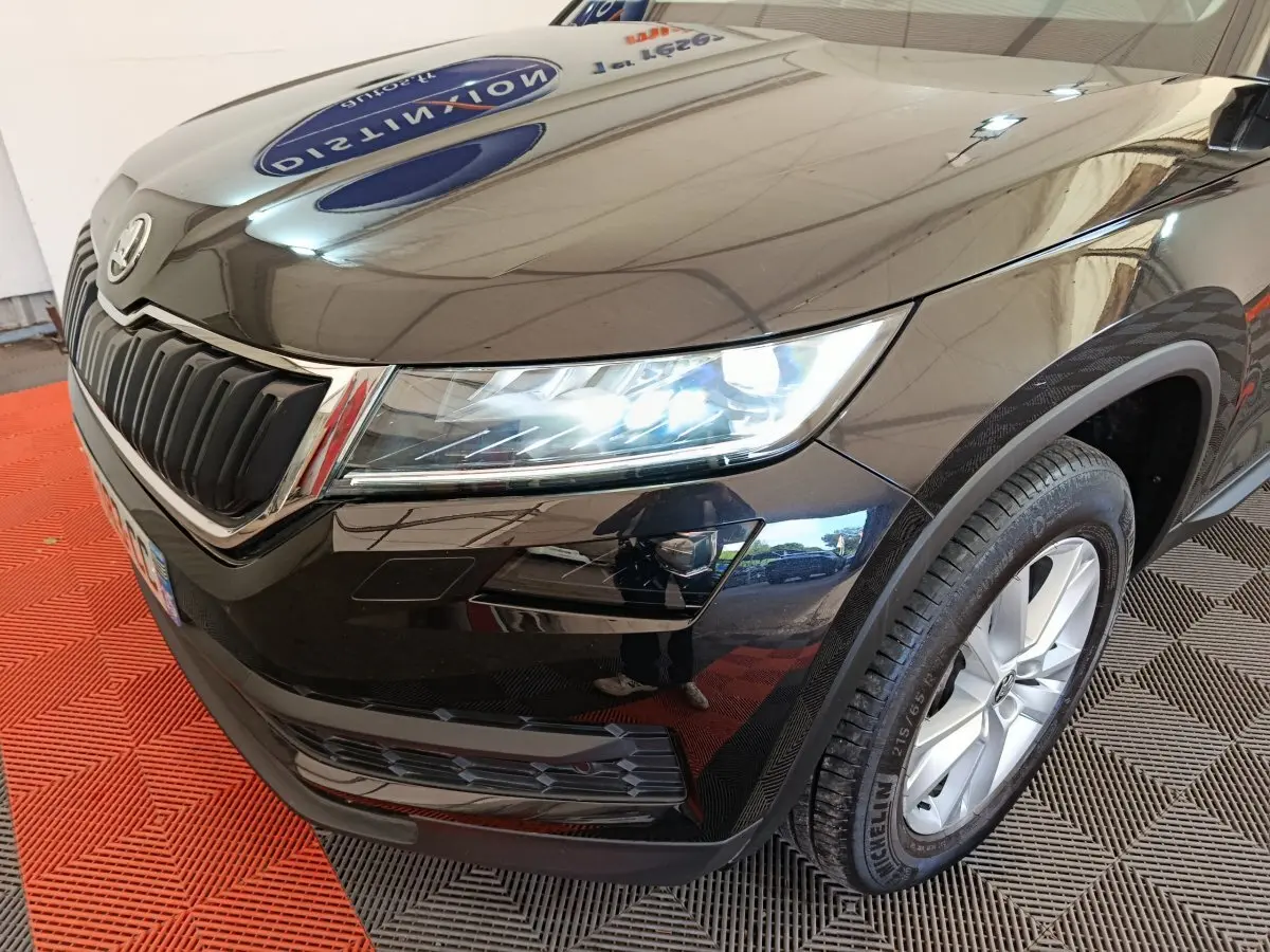 Vue 3/4 avant droit d'un Skoda Kodiaq noir avec phares LED allumés et jantes alliage visibles.