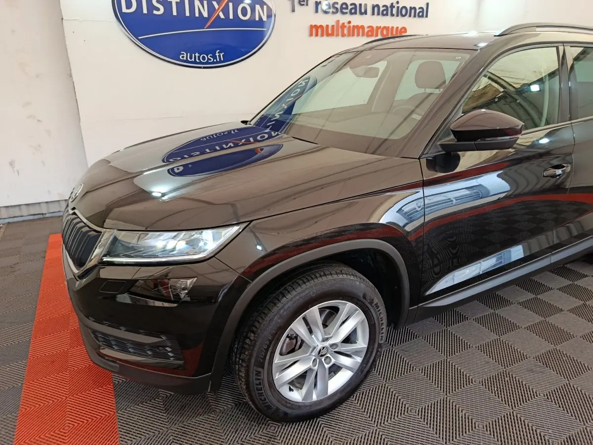 Vue 3/4 avant droit d'un Skoda Kodiaq noir brillant avec jantes alliage et phares LED dans un showroom.