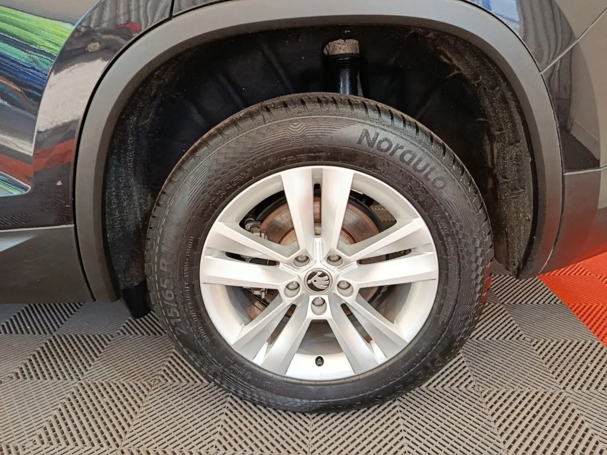 Gros plan sur la roue avant droite noire d'un Skoda Kodiaq 2021 avec jante argentée à 5 doubles branches.