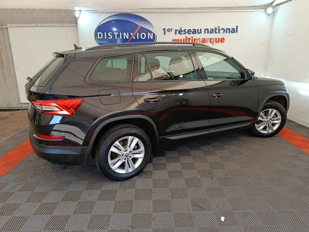 Vue latérale droite d'un SKODA KODIAQ noir 2021 avec jantes alliage et toit noir dans un showroom.