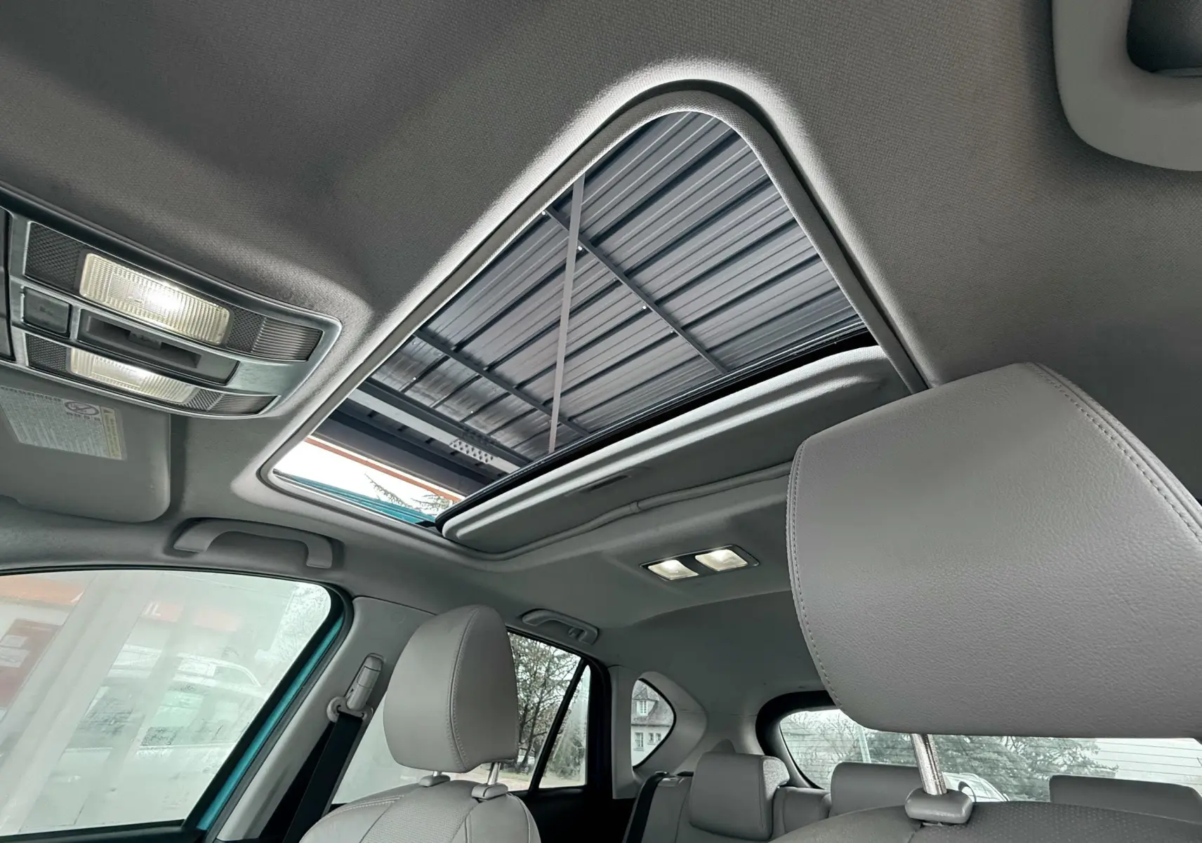 Toit ouvrant panoramique ouvert vu de l'intérieur avant du Mazda CX-5 2013, sièges en cuir gris clair.