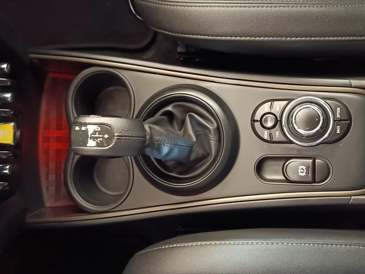 Vue rapprochée de la console centrale noire du MINI Countryman Cooper SE avec levier de vitesses et commandes multifonctions.